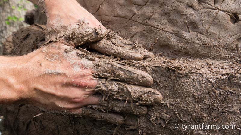 Putting cob over the clay layer. The clay layer provides lots of radiative heat while the cob layer provides more insulation, keeping the heat in.
