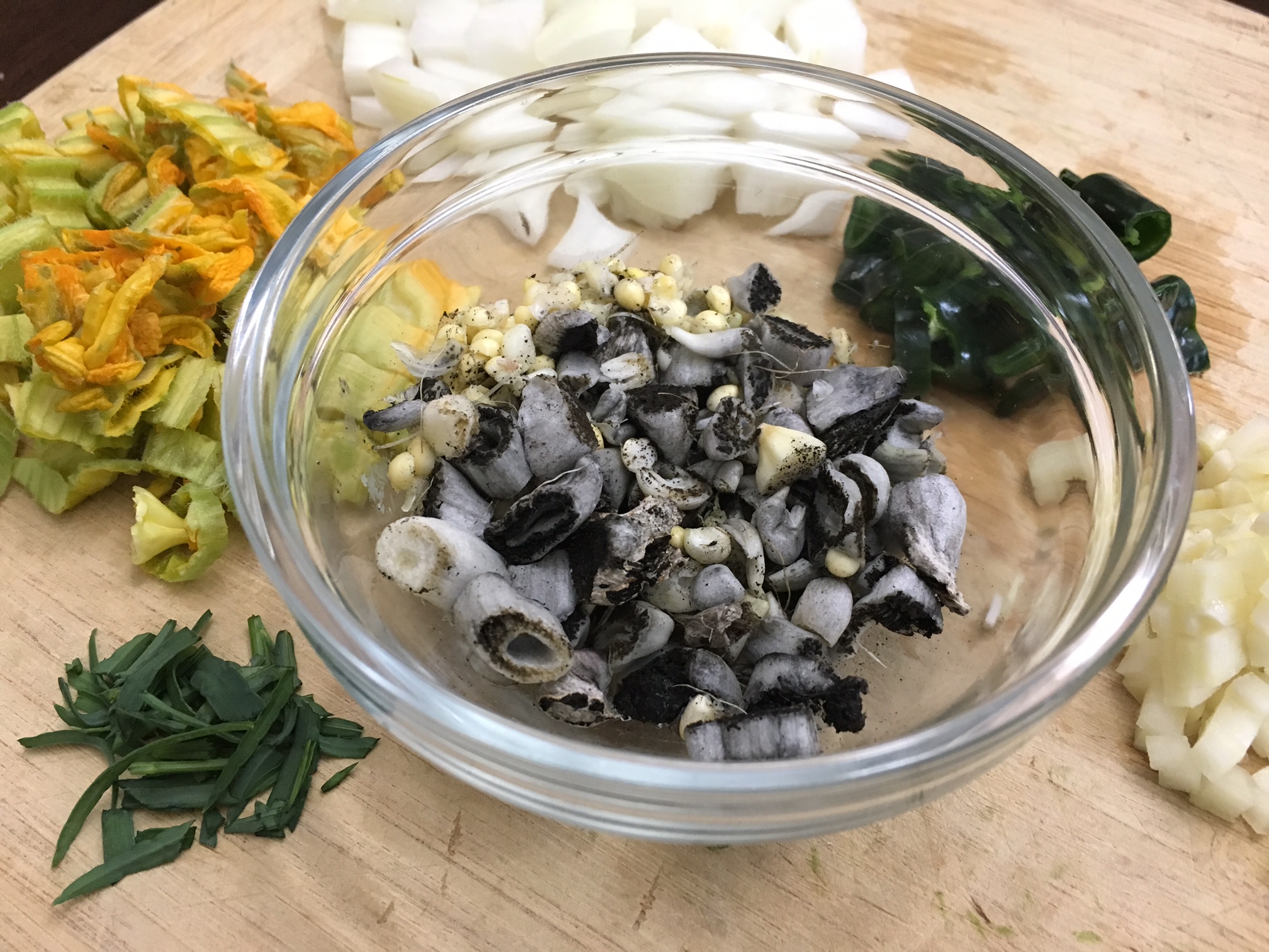 Some of the primary garden-fresh ingredients for huitlacoche soup, clockwise: pipicha (herb), squash flowers, onions, chile pepper, hardneck garlic. 