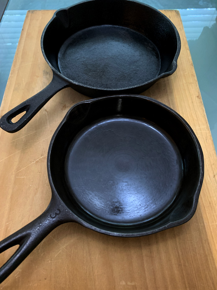 Just by looking at the pan surface, you can tell the antique cast iron pan (front) from the new cast iron pan (back). Note the glass-smooth bottom of the antique pan vs the pebbly bottom of the new pan.
