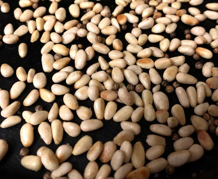 Pine nuts and coriander toasting in a cast iron skillet. Your eyes and nose will tell you when they're done.
