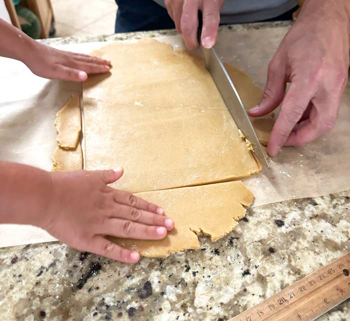 Toddler hands helping dad hands remove extra dough from the outside.