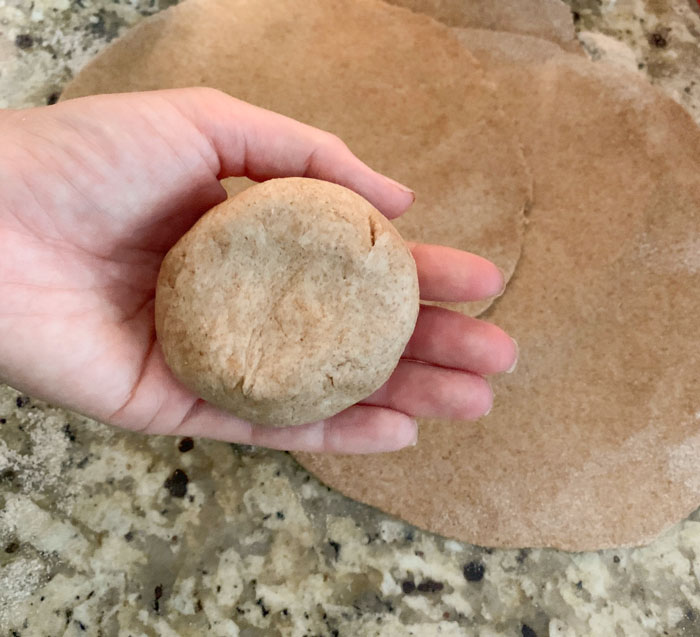 This image shows: 1) the ideal consistency of the dough when it's ready to start using, and 2) the size of the dough balls you should start with when rolling out individual flatbreads.