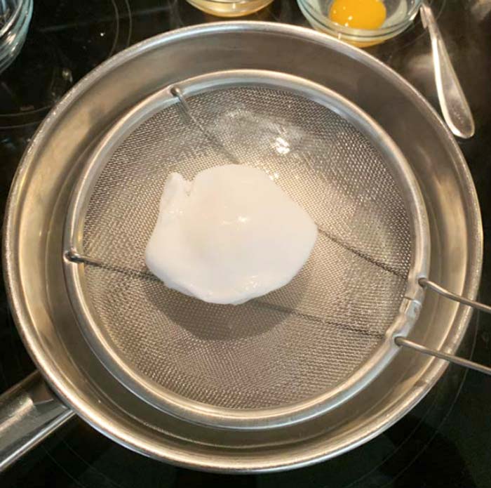 A perfectly poached duck egg being removed from the water.