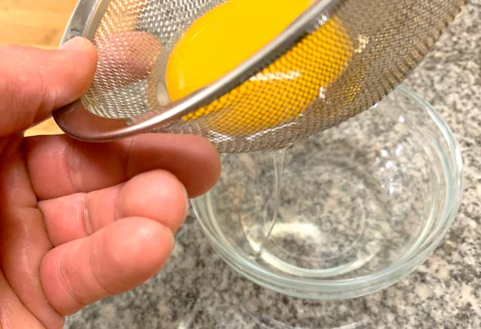 Straining out the watery parts of the whites before poaching a goose egg.