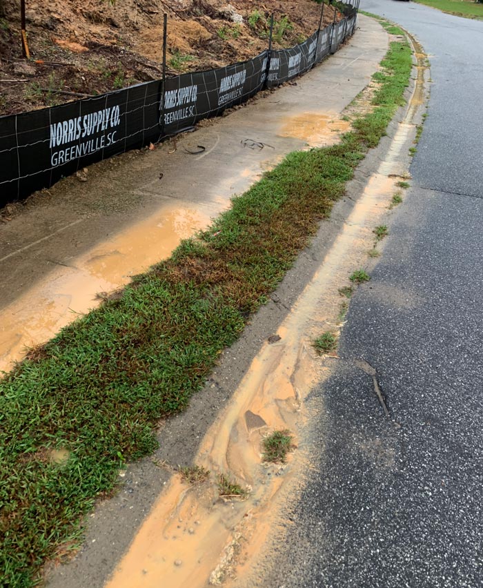 Silt and mud running off of a new construction site during heavy rains despite a barrier.