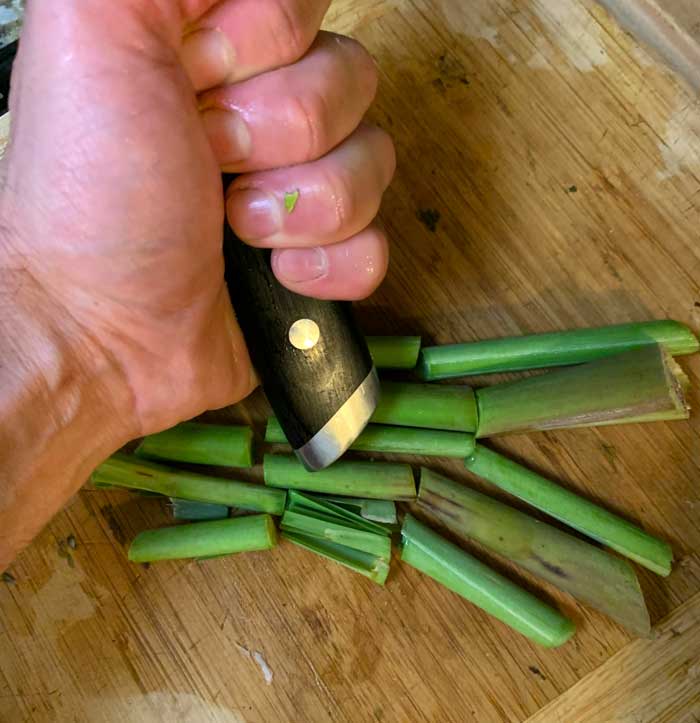 Smashing lemongrass sections for optimal flavor extraction. 
