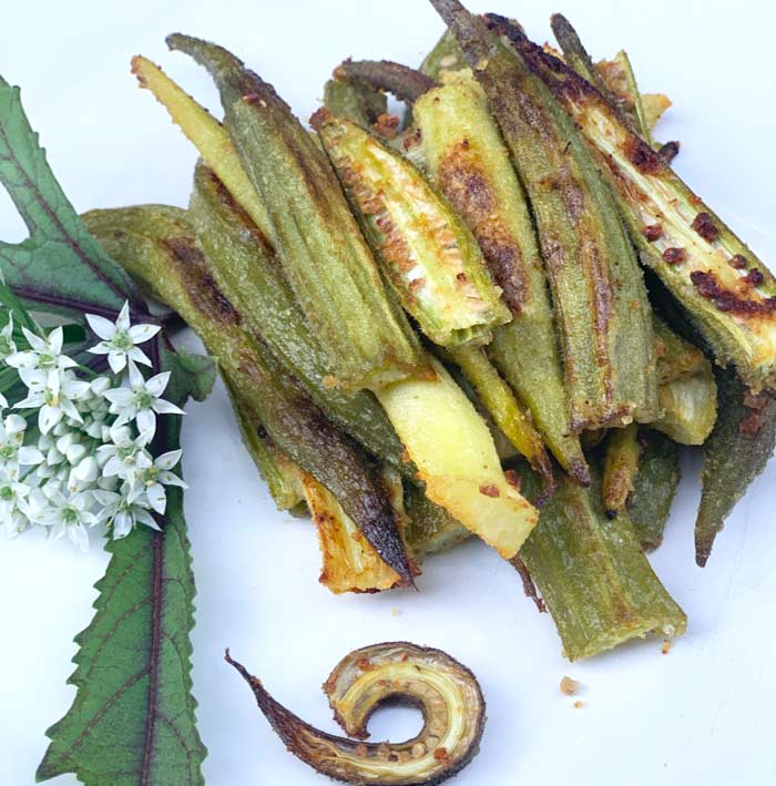 Oven-baked okra. Decorative additions to the plate are garlic chive flowers and red okra leaves - both of which are also edible.