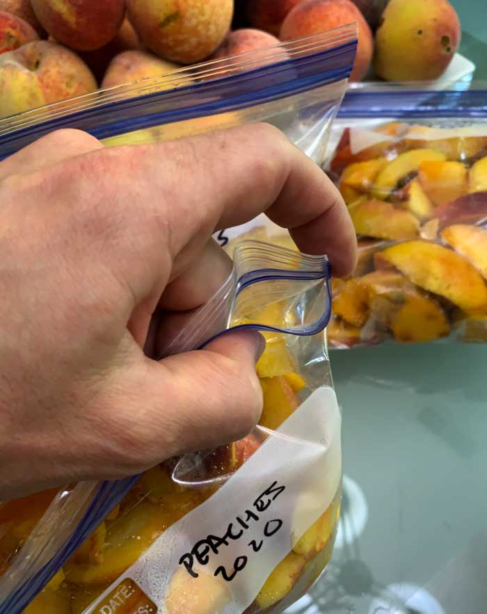 Peach freezer storage tip: you can do a DIY vacuum seal on your bags of peaches by zipping shut all but one corner of a ziploc. Then suck the air out with your mouth and quickly zip the small hole shut. 