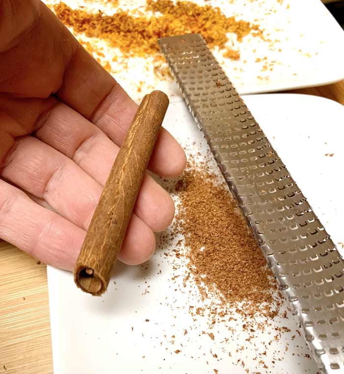 Fresh grated cinnamon from a microplane. Orange zest in the background. Freshly grated ingredients add more and better flavor to any recipe.