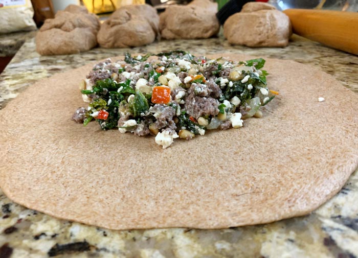Roll out each poğaça dough ball and add the filling into the center.