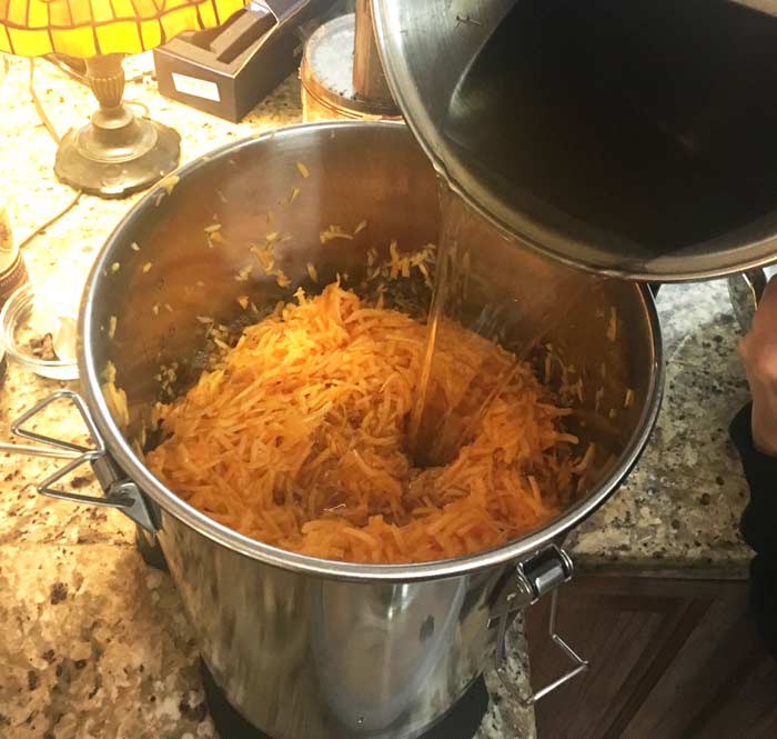 Adding the sugar water - which the yeast digests and converts to alcohol along with the sugar in the pumpkin.