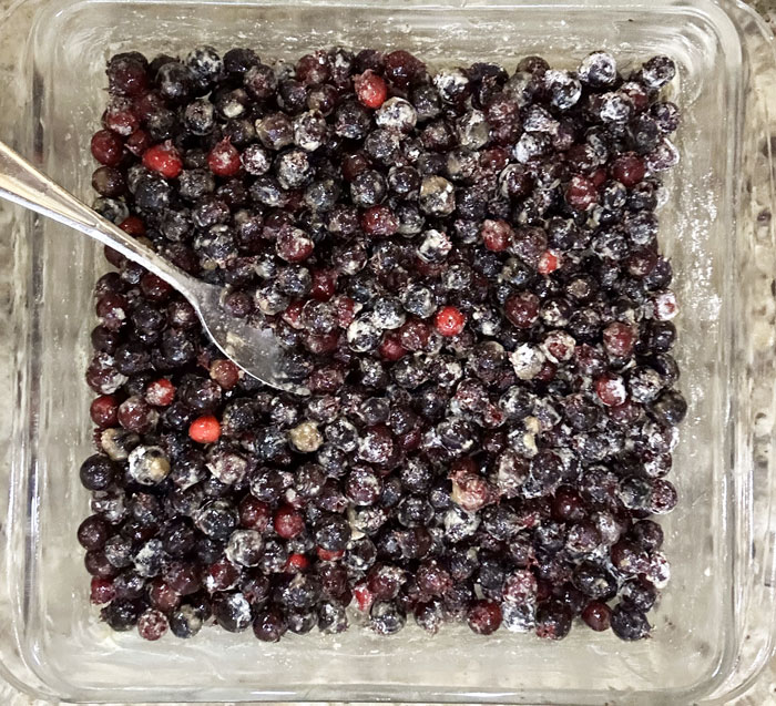 Coated serviceberries in baking dish.