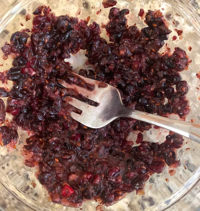 Smashing serviceberries with a large serving fork.