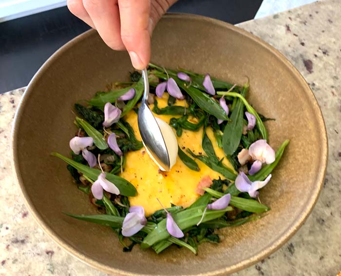 Chef David putting the final touches on soft-scrambled eggs with wilted collejas and stinging nettles.