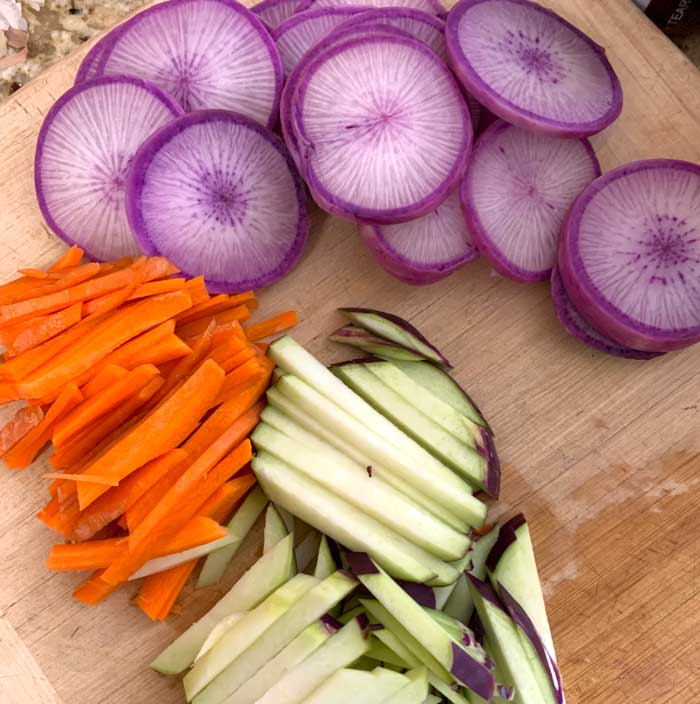 Chopstick cut purple kohlrabi and carrots (bottom) with a few round cuts of radishes (top) set aside to showcase their beauty.
