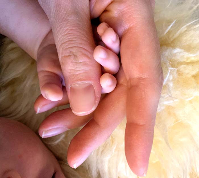 Susan holding Sebastian's tiny baby hand.