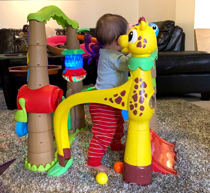 Baby Sebastian pushing balls down the slide of his Little Tikes activity center.