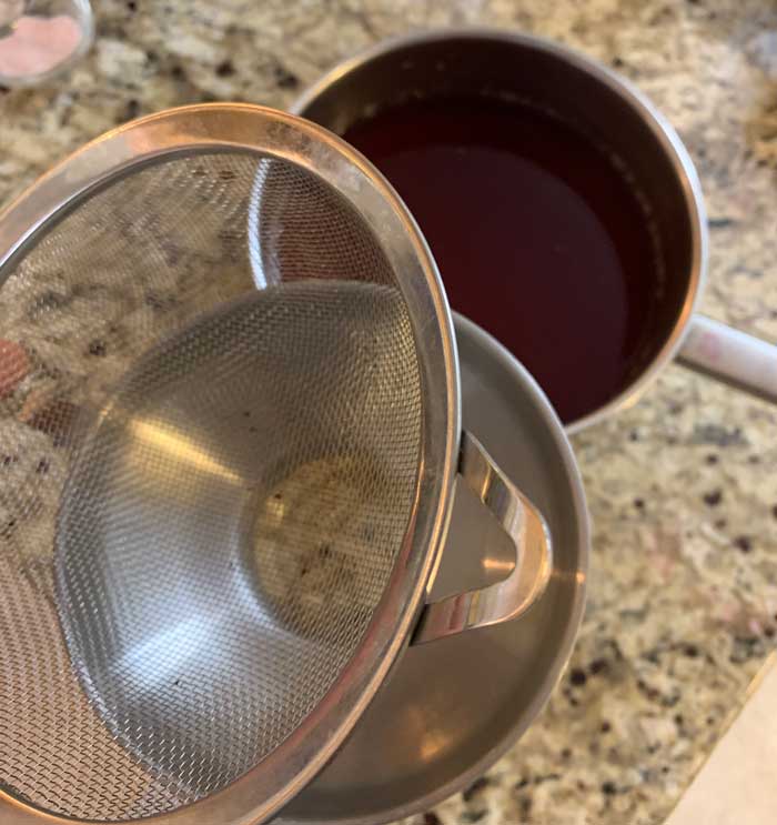 Preparing for a second finer strain to remove any additional sediment as the beautyberry juice is poured into jars.