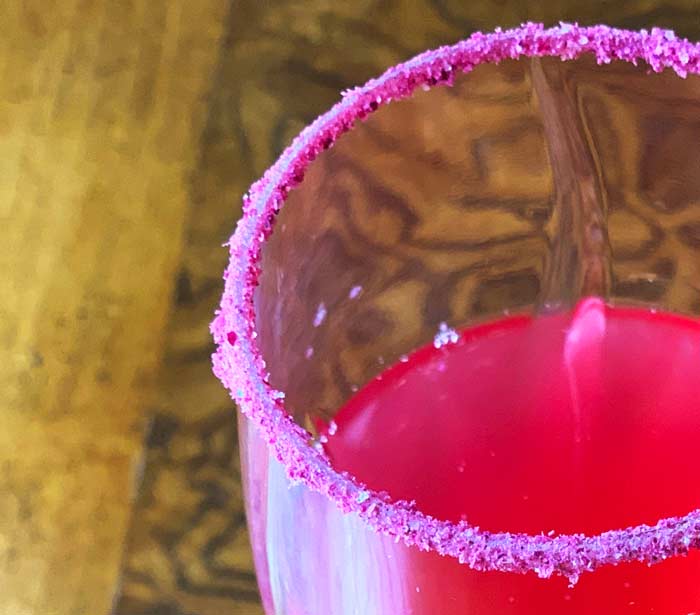 Fermented rose cordial served in a glass rimmed with fermented rose blossom powder.