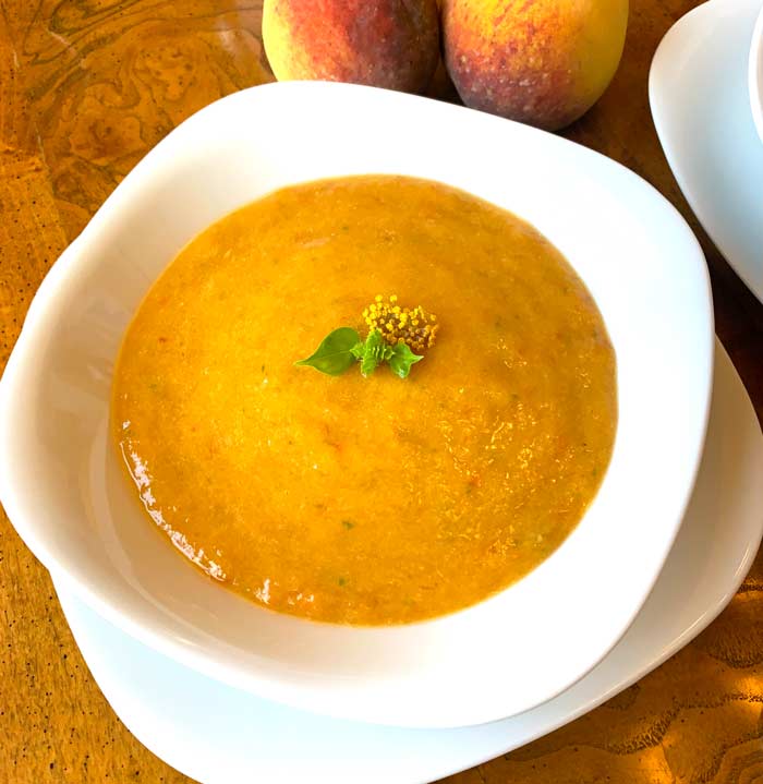 Peach gazpacho served chilled with a topping of immature basil flower buds and bronze fennel flowers.