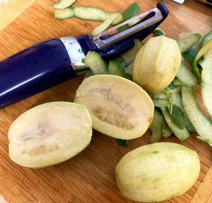 Removing skins from larger pineapple guava fruits before slicing and serving. How to eat pineapple guava fruit.